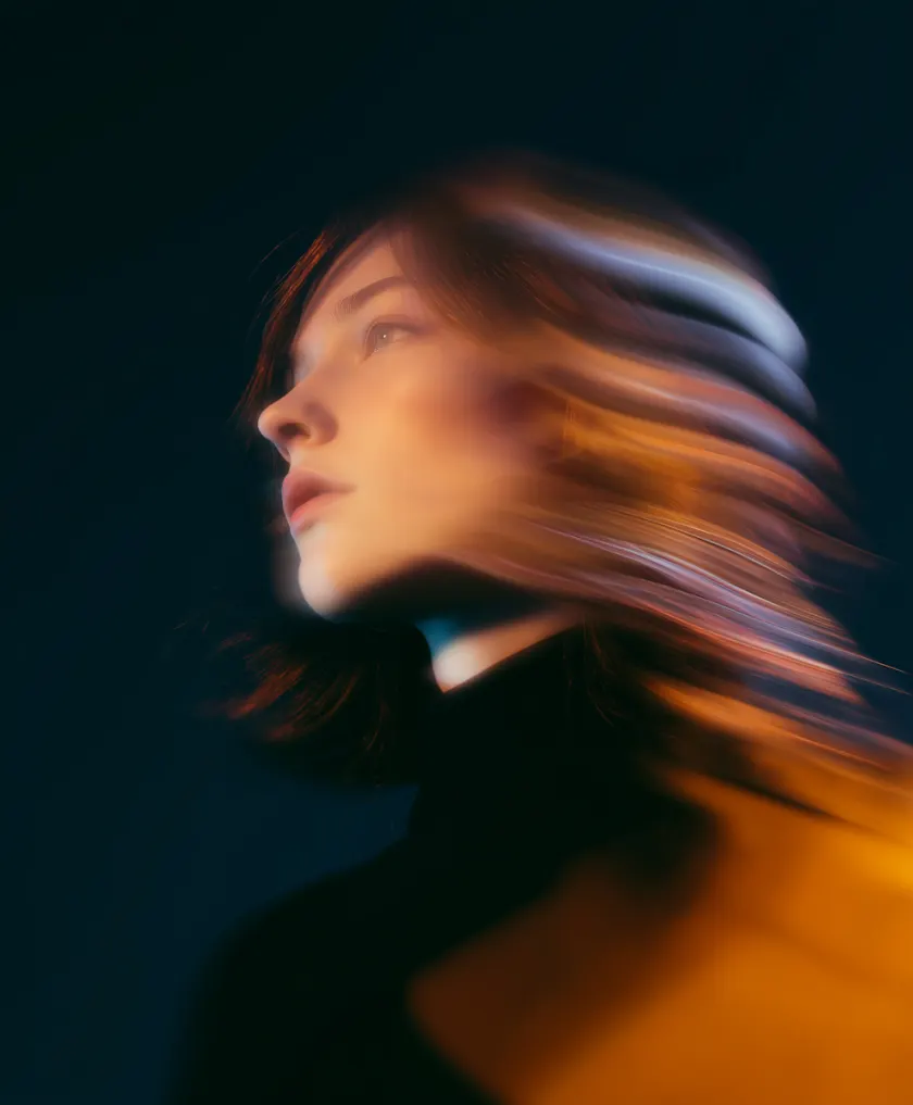 Profile of a woman with motion-blurred hair against a dark background